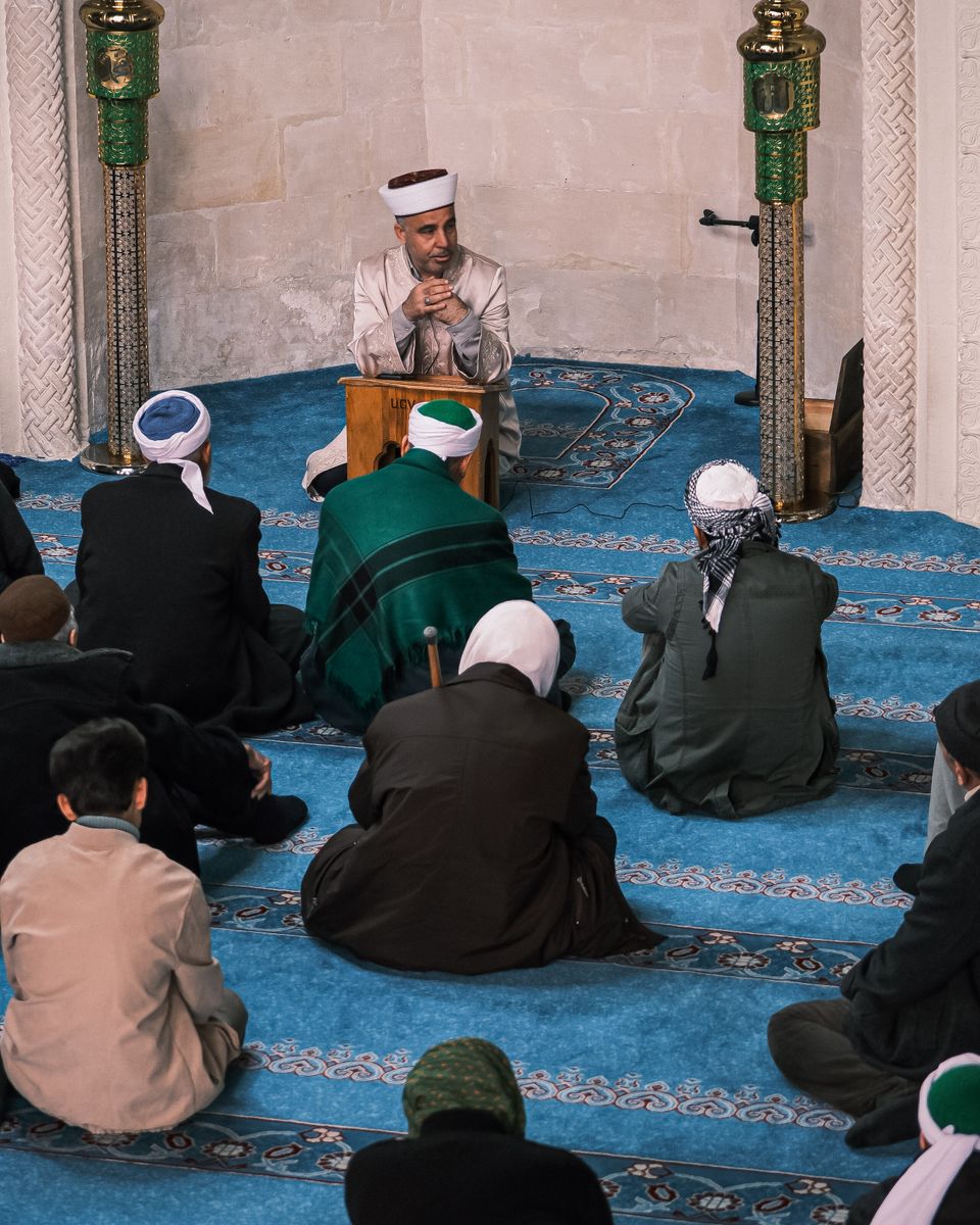 A congregation seated inside a mosque listening to a talk